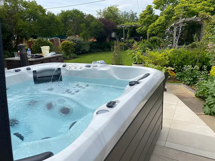 Outdoor hot tub with clear blue water in a landscaped garden.