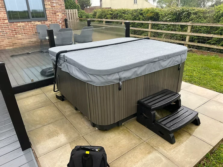 Grey insulated hot tub cover fitted to an outdoor spa.